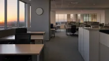 Oficina moderna con puestos de trabajo y vistas al atardecer desde las ventanas