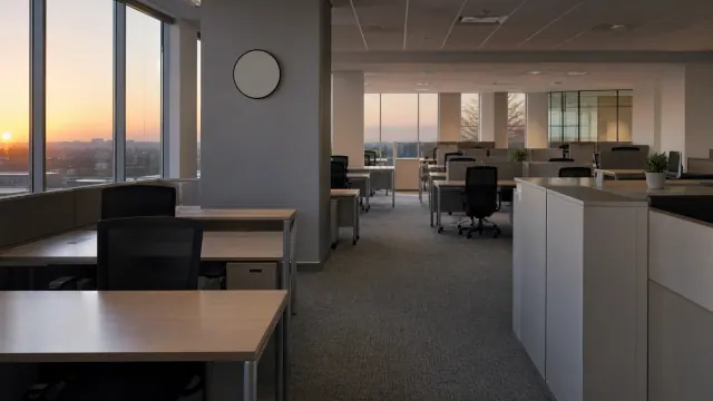 Oficina moderna con puestos de trabajo y vistas al atardecer desde las ventanas