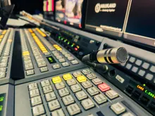Sala de control de un estudio de televisión con monitores apagados y mesa de mezclas