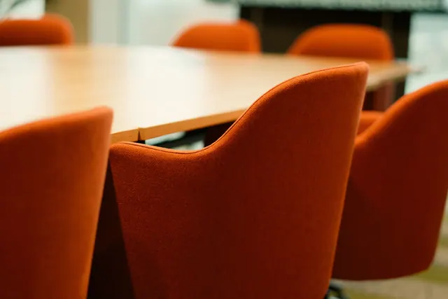 Mesa de reuniones vacía con sillas en una sala de consejo