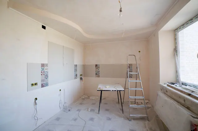 Habitación en obras con escalera, mesa de trabajo y azulejos a medio colocar
