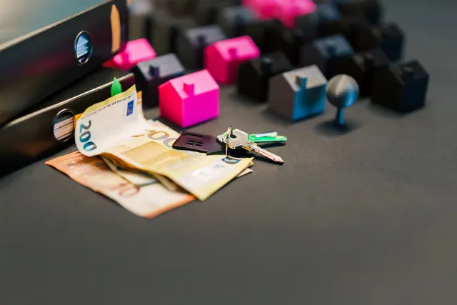 Billetes de euro, llaves y miniaturas de casas sobre una mesa
