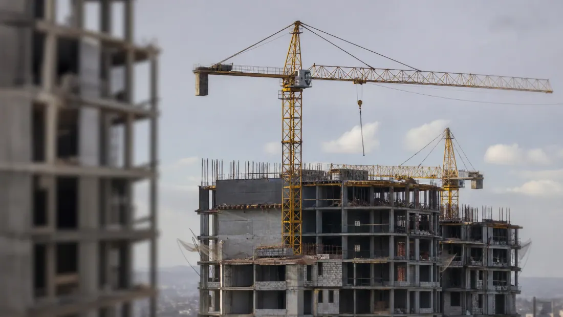 Edificio de apartamentos en construcción con grúas y estructura de hormigón sin terminar