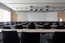 Sala de conferencias vacía con filas de mesas y sillas