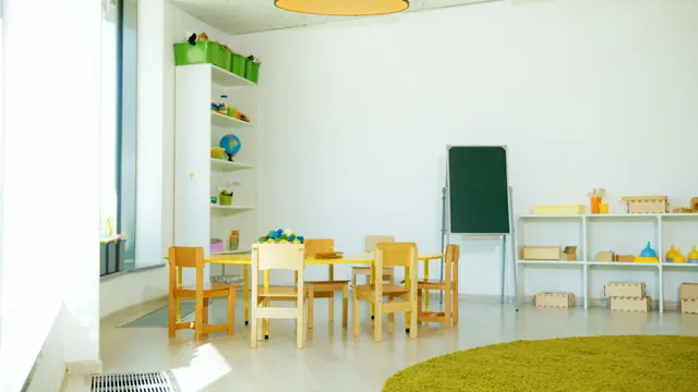 Aula infantil vacía con mesas, sillas y una pizarra