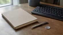 Cuaderno de hojas en blanco sobre escritorio de madera junto a bolígrafo y teclado