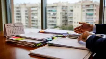 Una persona trabajando en un escritorio con documentos y calendario frente