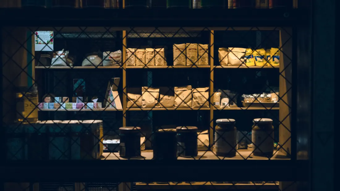 Estantería de una tienda con productos envasados tras una reja