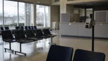Sala de espera de un centro médico con sillas negras y mostrador de recepción