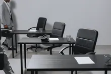 Una persona camina junto a varias mesas vacías con sillas de oficina