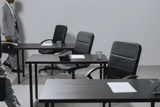 Una persona camina junto a varias mesas vacías con sillas de oficina