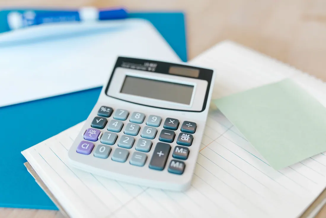 Una calculadora sobre un cuaderno y una carpeta azul
