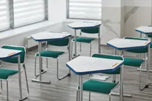 Pupitres individuales con exámenes dispuestos en un aula vacía