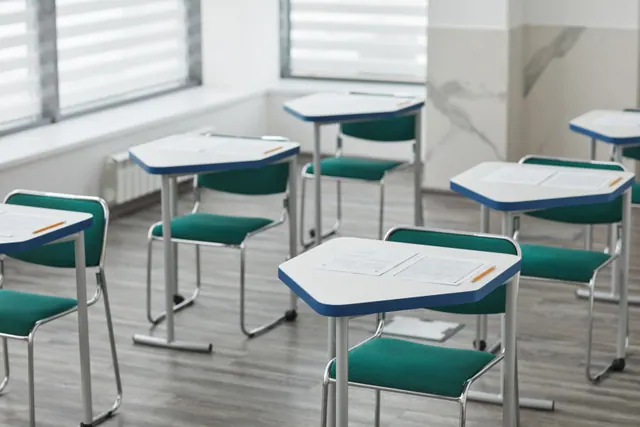 Pupitres individuales con exámenes dispuestos en un aula vacía
