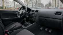 Interior de vehículo con volante, salpicadero y asientos de tela oscura