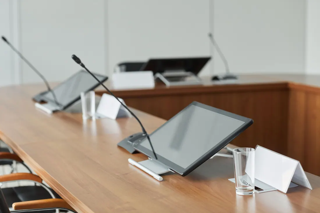 Sala de reuniones con pantallas y micrófonos sobre una mesa
