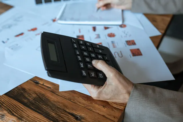 Una persona usa una calculadora sobre una mesa con gráficos impresos