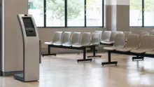 Terminal de autoservicio en sala de espera con asientos de espera