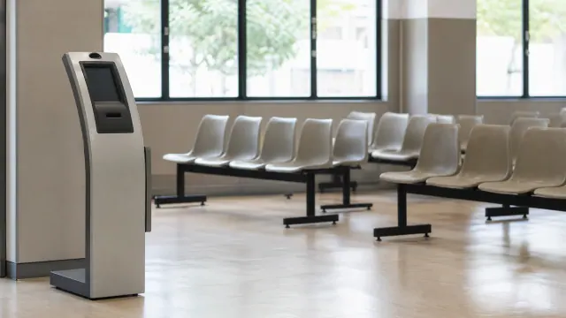 Terminal de autoservicio en sala de espera con asientos de espera