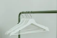 Perchas blancas colgadas en un perchero de metal verde