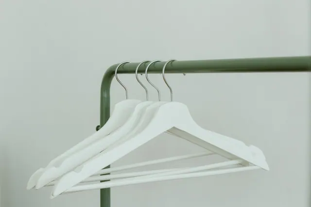 Perchas blancas colgadas en un perchero de metal verde