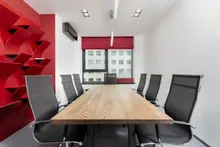 Sala de reuniones vacía con mesa de madera y sillas negras