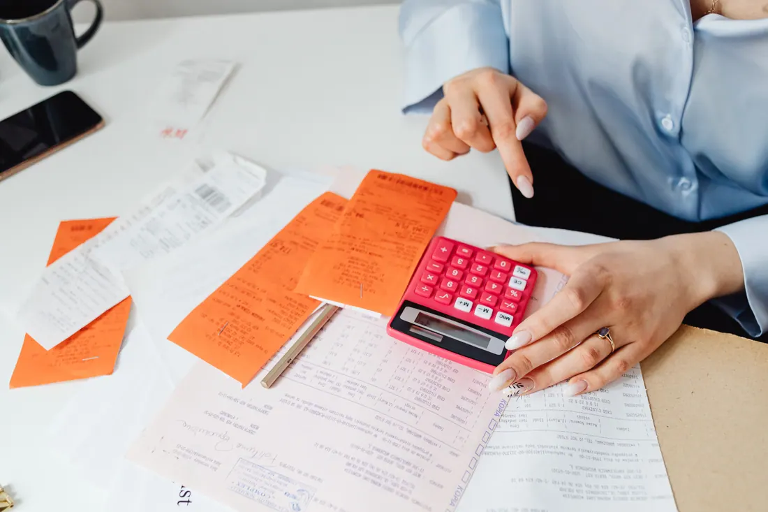 Una persona revisa recibos y factura con una calculadora en un escritorio