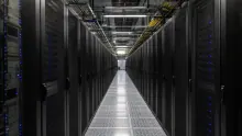 Pasillo central de un centro de datos con racks de servidores negros a ambos lados