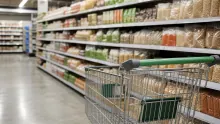 Carrito de compra frente a estantes de productos secos en supermercado