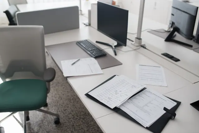 Escritorios de oficina con ordenadores y documentos sobre las mesas