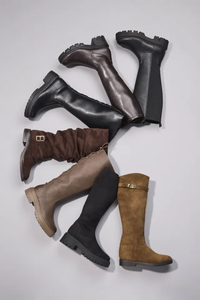 Composición de botas de piel en tonos negros, marrones y tostados con suelas de goma gruesa, dispuestas en diagonal