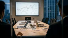 Personas en una sala de reuniones observan gráficos financieros en pantalla