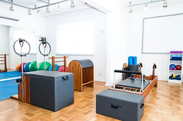 Sala de ejercicio vacía con suelo de madera, esterillas enrolladas y luz natural suave