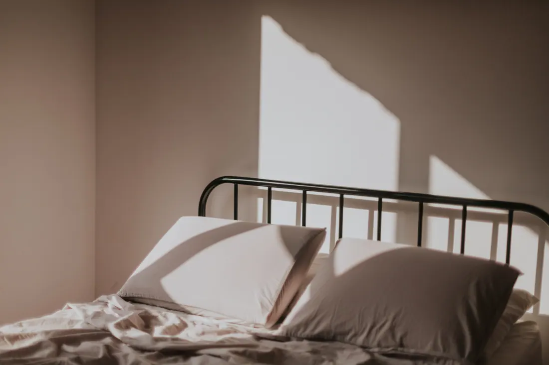 Cama con cabecero metálico iluminada por luz solar