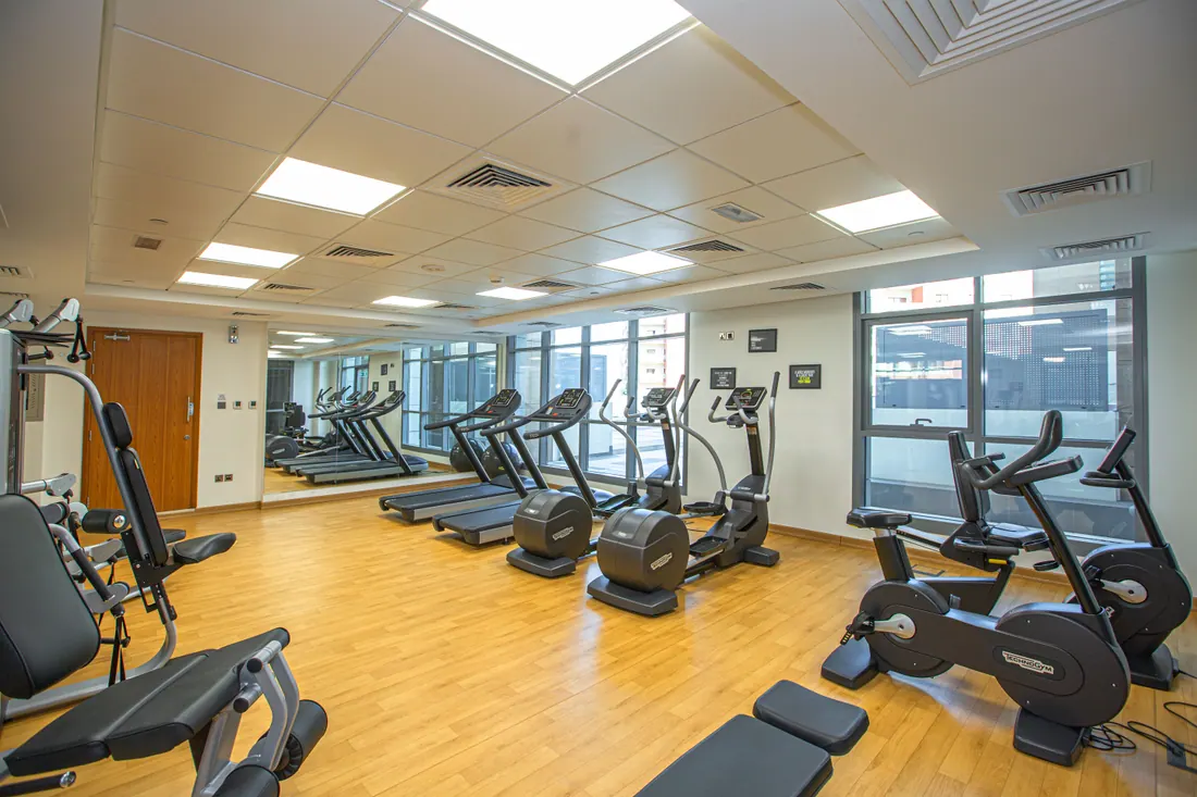 Gimnasio con máquinas de cardio junto a ventanales