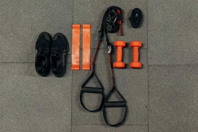 Material deportivo colocado en el suelo: zapatillas, bandas y pesas