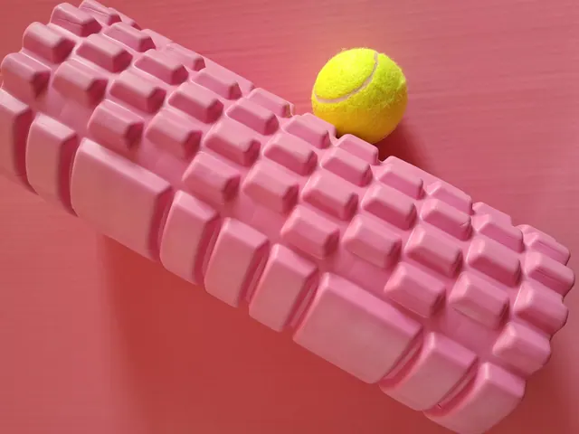 Rodillo de masaje de espuma junto a una pelota de tenis