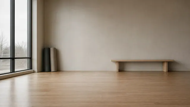 Interior minimalista con suelo de madera, banco bajo y cilindros negros junto