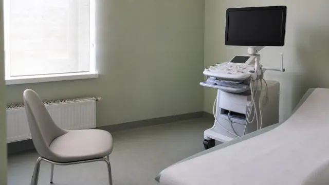 Equipo de ecografía en una consulta médica con silla de espera