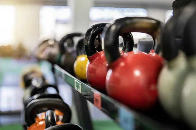 Kettlebells de colores alineados en un estante de gimnasio