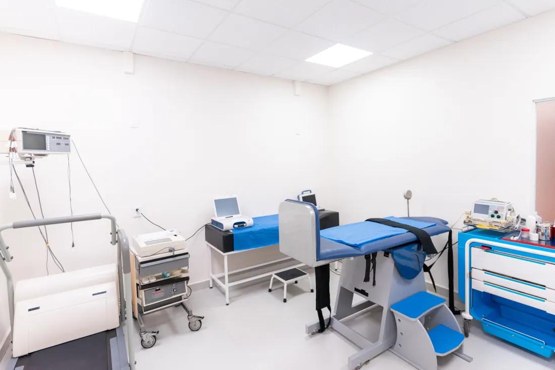 Sala de exploración médica con camilla inclinable y equipos clínicos