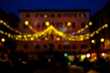Plaza nocturna decorada con guirnaldas amarillas de luces, fachada de edificio histórico al fondo