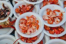 Platos de gambas y marisco cocido servidos en bandejas desechables