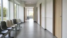 Pasillo de clínica u hospital con sillas de espera y puertas de consultorios