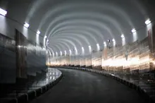 Interior de un túnel moderno con bóveda cilíndrica iluminada por luces laterales y suelo reflectante