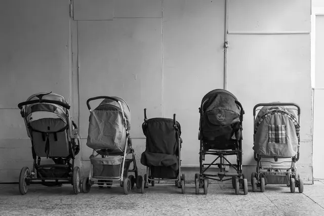 Cinco carritos de bebé vacíos alineados contra una pared