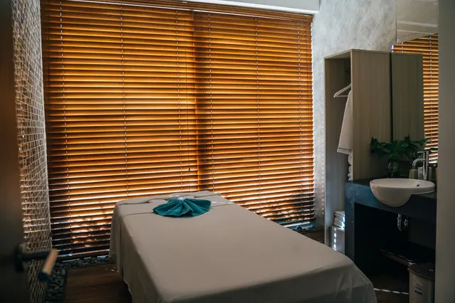 Camilla de masajes en una sala de spa con persianas de madera