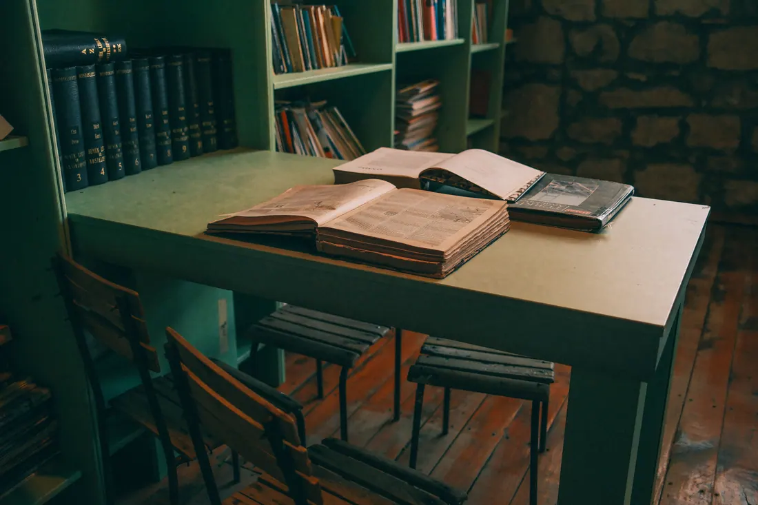 Mesa de biblioteca con libros y periódicos antiguos abiertos
