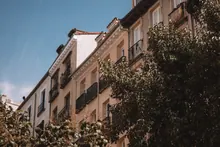 Elegante edificio residencial con balcones rodeado de árboles frondosos