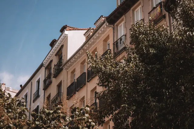 Elegante edificio residencial con balcones rodeado de árboles frondosos